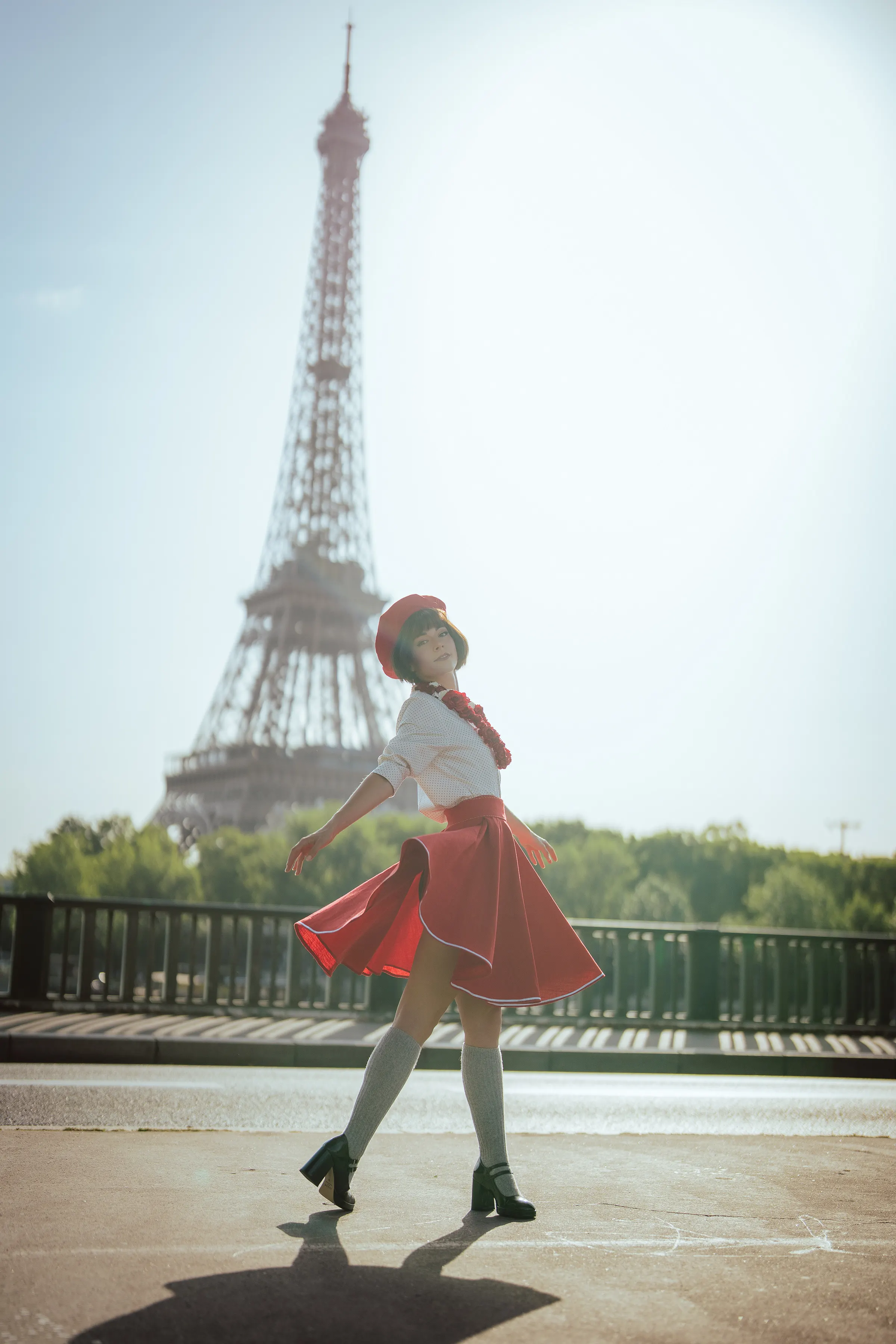 Sophie de Clair Obscur: Expédition 33, en jupe rouge et béret, marchant devant la Tour Eiffel, cosplay Ryuu Seika